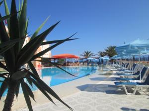 a swimming pool with lounge chairs and umbrellas at Ninos On The Beach Hotel in Roda