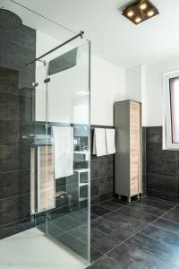 y baño con ducha de cristal y azulejos negros. en Apartment Griass di Fügen en Fügen