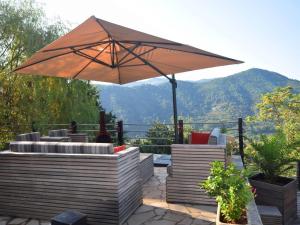 a patio with an umbrella and chairs with a view at Modern holiday home with swimming pool in Saint-Fortunat-sur-Eyrieux