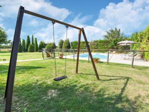 a swing set in a yard with a pool at Belvilla by OYO Chiaraquattro in Acquaviva