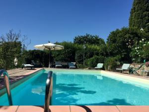 einen Pool mit Sonnenschirm und Stühlen in der Unterkunft Belvilla by OYO Il Fienile in Monterchi