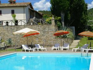 una piscina con sedie e ombrelloni accanto a una casa di Beautiful apartment with private terrace and panoramic swimming pool a Parnacciano