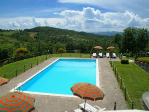 una piscina con due ombrelloni e sedie di Beautiful apartment with private terrace and panoramic swimming pool a Parnacciano