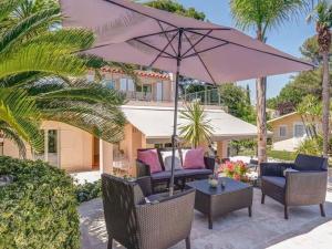 a patio with chairs and an umbrella and a table at Lavish Villa in Mouans Sartoux with Sauna in Mouans-Sartoux