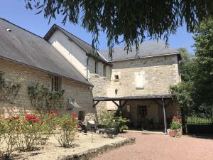 an old stone building with a courtyard with flowers at Former customs house with large garden and private pool 4 km from Chinon in La Roche-Clermault
