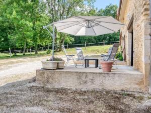 Villefranche-du-PérigordにあるCozy Holiday Home in Loubejac near Forestのパティオ(テーブル、椅子、パラソル付)