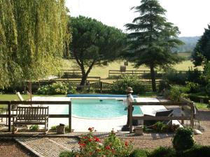 a swimming pool in a garden with benches and trees at Former customs house with large garden and private pool 4 km from Chinon in La Roche-Clermault