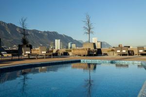 a swimming pool with chairs and mountains in the background at Camino Real Fashion Drive Monterrey in Monterrey