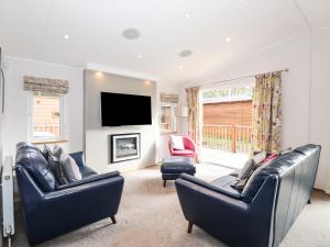 a living room with two leather chairs and a flat screen tv at Ridgway Lodge in Windermere