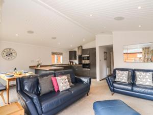 a living room with two leather couches and a kitchen at Ridgway Lodge in Windermere