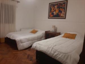 a room with two beds and a picture on the wall at Casa frente al parque San Martín zona residencial in Mendoza