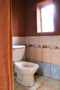 a bathroom with a toilet and a window at TAQUILE LODGE - Un lugar de ensueño in Huillanopampa