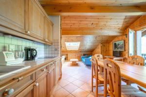 eine Küche mit Holzschränken sowie einem Tisch und Stühlen in der Unterkunft Gentiane Furnished flat in Les Houches