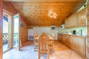 eine Küche mit Holzschränken sowie einem Tisch und Stühlen in der Unterkunft Gentiane Furnished flat in Les Houches