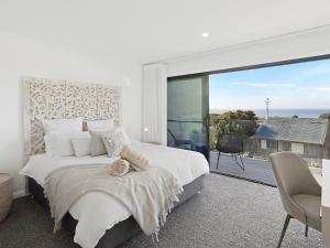 a white bedroom with a large bed and a large window at Ocean Scene in Fingal Bay