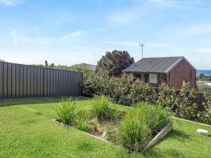 a garden with a brick house and a fence at Ocean Scene in Fingal Bay