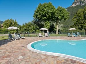 a swimming pool with chairs and umbrellas at Amazing Apartment in Idro with Shared Pool in Crone