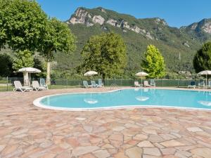 a swimming pool with chairs and umbrellas in front of a mountain at Amazing Apartment in Idro with Shared Pool in Crone