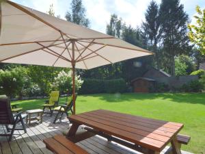 un tavolo in legno con ombrellone su un patio di Wooden villa on the Veluwe a Wissel
