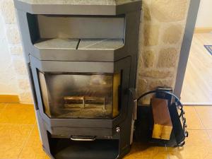 a stone fireplace with a stove in a room at Peaceful Forest Getaway in Altenfeld
