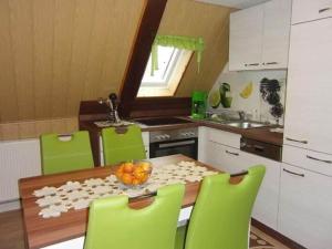 eine Küche mit einem Holztisch und grünen Stühlen in der Unterkunft Holiday home in Saxon Switzerland quiet location big garden grilling area in Lichtenhain