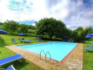 a large swimming pool with blue chairs and umbrellas at Belvilla by OYO Casa Ginepro in San Quirico dʼOrcia