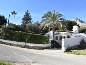 a white house with a fence and palm trees at Belvilla by OYO Villa Rivas in Jávea
