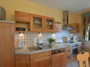 uma cozinha com armários de madeira e um lavatório em Cushy Apartment in Nohn with Terrace Garden BBQ em Nohn