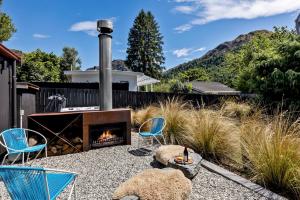 a patio with chairs and a fireplace in a yard at Arrowtown Red Cottage with Spa in Arrowtown
