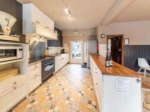 uma grande cozinha com armários brancos e piso em azulejo em Beautiful group house with large garden em Gouvy