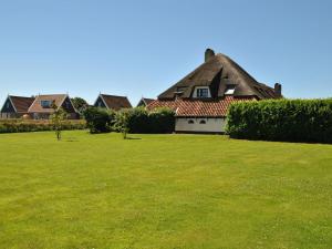 a house with a thatched roof and a grass field at Charming Holiday Home in Texel in Oost