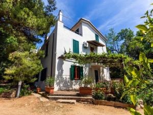 a white house with green shutters and potted plants at Spacious Villa in Calabria with Swimming Pool in Ricadi