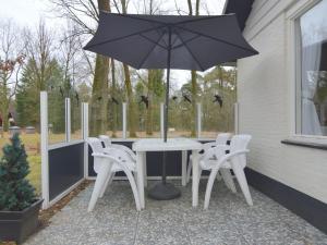 StramproyにあるSerene Holiday Home in Limburg amid a Forestのパティオ(パラソル付きのテーブルと椅子付)