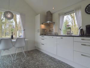 StramproyにあるSerene Holiday Home in Limburg amid a Forestの白いキャビネット、テーブルと椅子付きのキッチンが備わります。