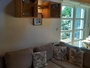 a couch with pillows in a living room with a window at Cottage in Durbuy with Terrace Garden Barbecue in Durbuy