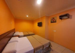 two beds in a room with yellow walls at Highway Budget Hotel in Ipoh