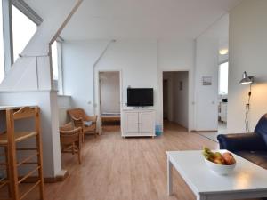 een woonkamer met een bank en een tv bij Apartment with stunning views in Bergen aan Zee