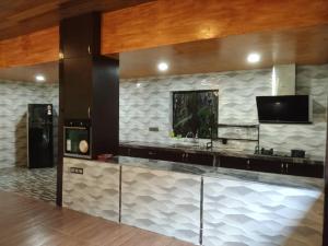 cocina con encimera y TV en la pared en Kemuning Orchard Villaa en Kerling