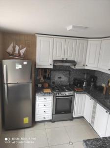 una cocina con nevera de acero inoxidable y armarios blancos en Casa completa SAME Casa Blanca en Same