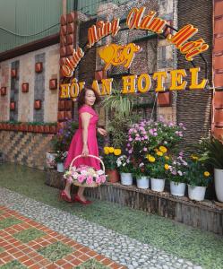 a woman in a pink dress holding a basket of flowers at Khách sạn Hội An - Kon Tum in Kon Tum