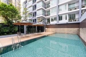 a swimming pool with chairs and umbrellas next to a building at Arize Hotel Sukhumvit in Bangkok
