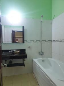 a bathroom with a tub and a sink and a mirror at Khách sạn Hội An - Kon Tum in Kon Tum