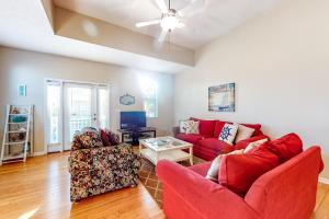a living room with a red couch and two chairs at Smiles N Waves in Panama City Beach