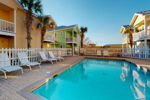 a swimming pool with chairs and a house at Smiles N Waves in Panama City Beach
