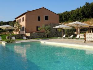 a swimming pool with chairs and umbrellas in front of a house at Farmhouse in Montoro near Montoro Castle in Narni