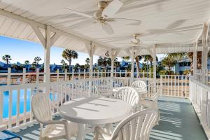 una mesa blanca y sillas en un porche con vistas al océano en Sunnyside Beach & Tennis #54, en Panama City Beach