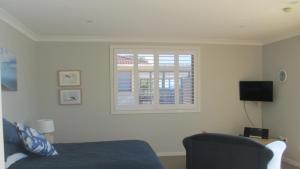 a bedroom with a bed and a window at HIBBARD HAVEN in Port Macquarie