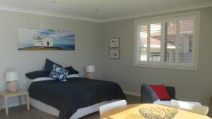 a bedroom with a bed and a table and a window at HIBBARD HAVEN in Port Macquarie