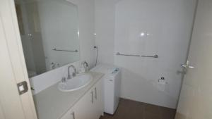 a white bathroom with a sink and a mirror at HIBBARD HAVEN in Port Macquarie