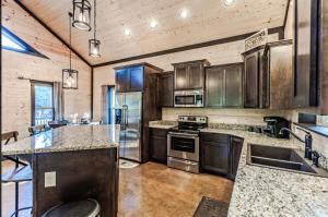 a kitchen with stainless steel appliances and wooden cabinets at Knotty and Nice Luxury Cabin in Broken Bow